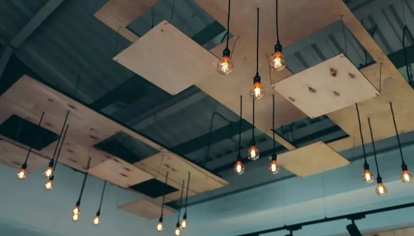 Moderna lampor hänger från ett tak med träpaneler, som om någon ville byta innertak och skapa en unik design.