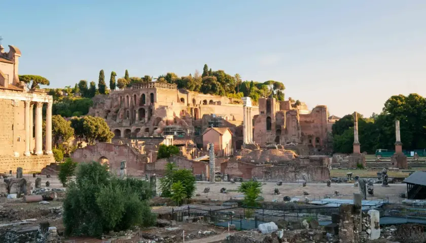 Ruines antiques sur le mont Palatin à Rome, baignées par la lumière dorée du soleil. Des colonnes brisées et des murs de briques témoignent de la grandeur passée.
