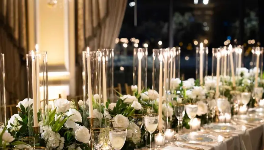 Elegancka dekoracja stołu weselnego z białymi kwiatami i świecami. Sprawdź, jaka jest florystka na wesele cena za takie cuda.