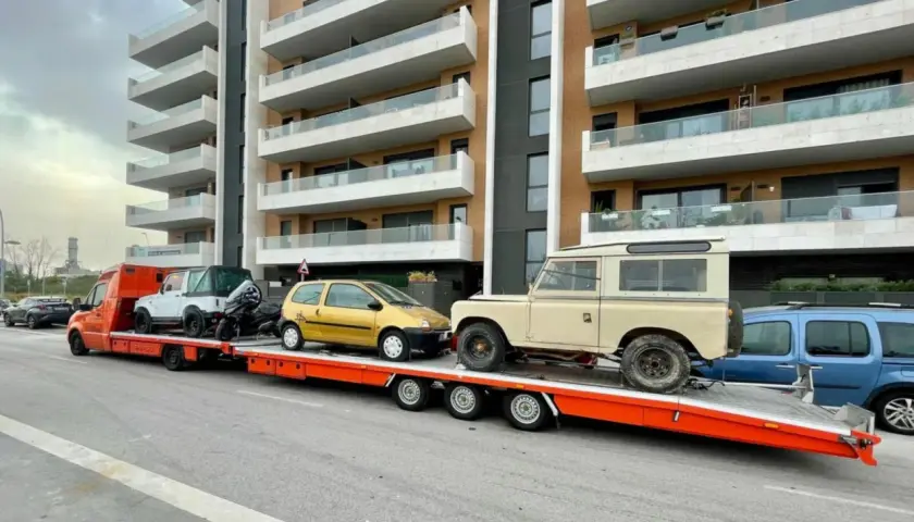 Laweta z autami: żółty Twingo, biały terenowy i beżowy Land Rover. B+E DMC.