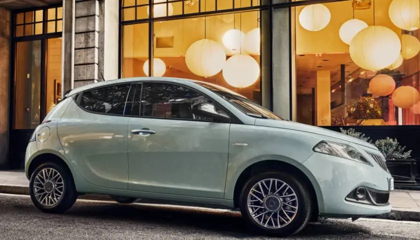 City car 5 posti azzurra parcheggiata davanti a una vetrina con lanterne luminose.
