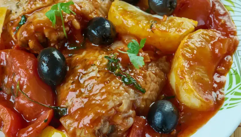 Un plat de daube de bœuf mijoté avec des tomates, des olives noires et des pommes de terre, garni de persil frais.