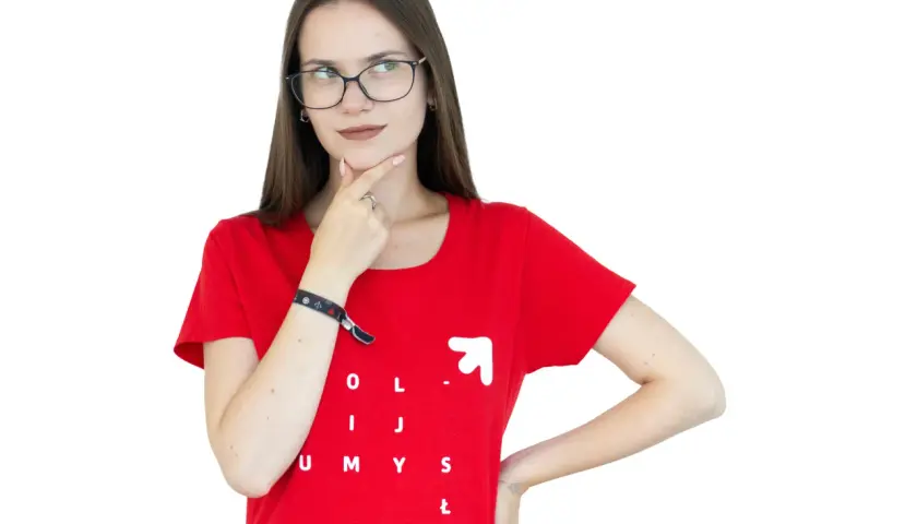 Młoda kobieta w okularach i czerwonej koszulce z napisem "OLIJ UMYSŁ" zastanawia się, czy jej pomysł jest ex aequo dobry jak inne.