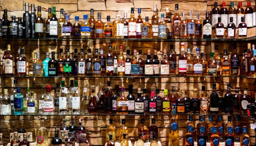 Étagères remplies de bouteilles de whisky et de champagne, un festin pour les amateurs de spiritueux.