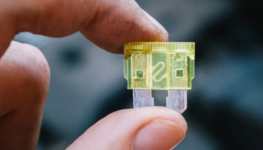 Dedo sostiene un fusible luz de freno amarillo de 20 amperios, listo para reemplazar uno quemado.