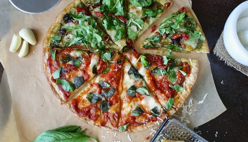 Dwie połówki pizzy: jedna z pesto i rukolą, druga z sosem pomidorowym i bazylią. Zastanawiasz się, ile kosztuje pizza w Czechach?