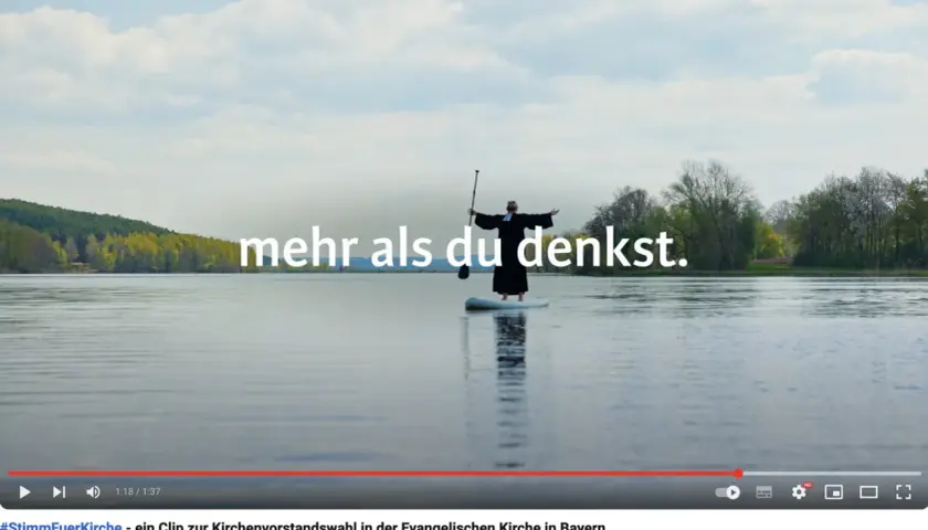 Ein Geistlicher steht auf einem SUP-Board auf einem See. Der Arbeitgeber Kirche bietet mehr als man denkt.