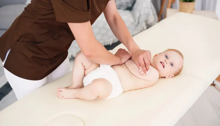 Niemowlę na masażu. Terapeuta wykonuje ćwiczenia metodą Vojty, stymulując rozwój dziecka.