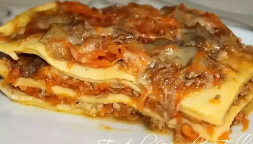 Une généreuse part de lasagne de canard, avec ses couches de pâtes, de viande effilochée et de sauce aux carottes, prête à être dégustée.