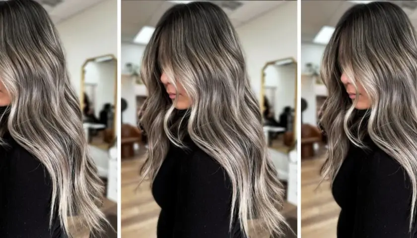 Pelo largo y ondulado con un degradado de color que combina canas y mechas rubias, creando un efecto moderno y natural.