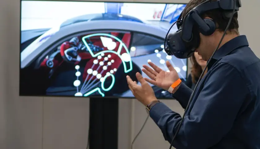 Un homme porte un casque de réalité augmentée, explorant un tableau de bord de voiture virtuel.