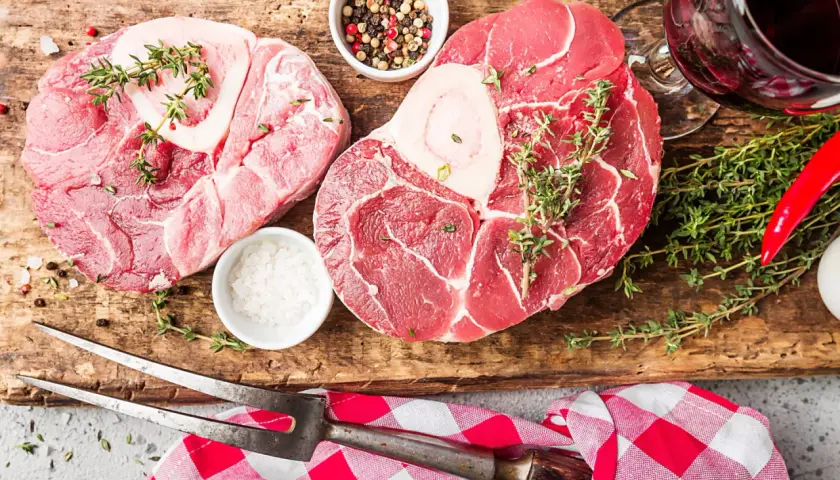 Deux belles pièces de viande blanche, du sel, des poivres, du thym et un piment rouge sur une planche en bois.