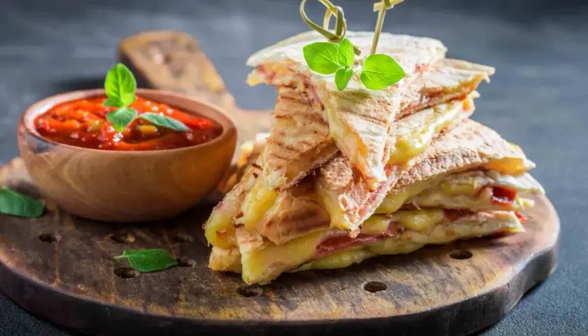 Pyszna tortilla z szynką i serem, podana z sosem pomidorowym. Idealna przekąska na szybki lunch.