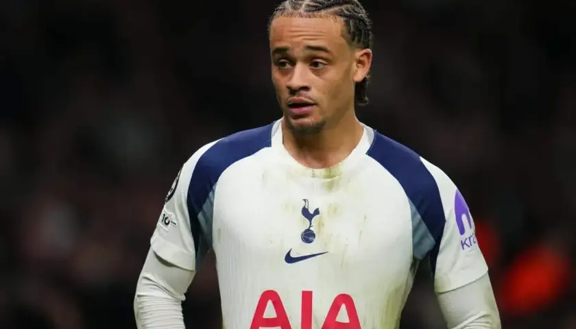 Piłkarz Tottenhamu w białej koszulce z granatowymi detalami, z charakterystyczną fryzurą.
