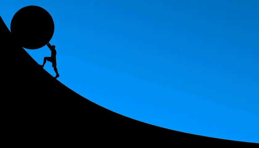 Silhouette d'un homme poussant une énorme sphère sur une pente. L'effort pour un prêt immobilier 30 ans.