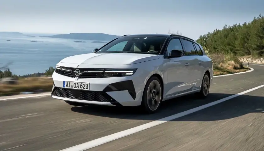 Biała Opel Astra Hybrid na krętej drodze nad morzem.