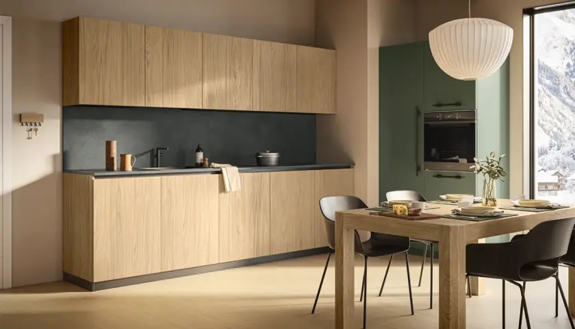 Un elegante montaggio cucina con ante in legno chiaro, piano scuro e un'isola centrale. La luce naturale illumina l'ambiente.