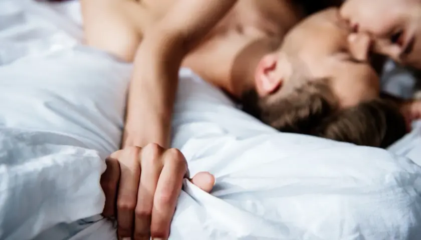Coppia in intimità, un momento di passione e masturbazione di coppia tra lenzuola bianche.