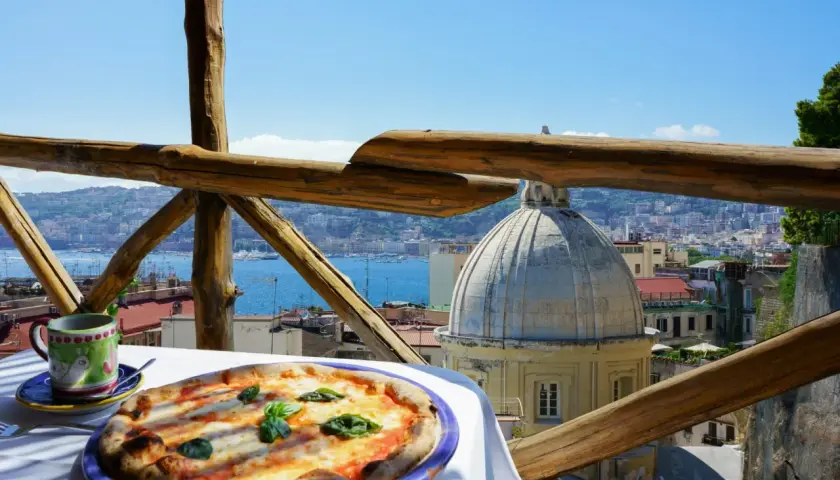 Pizza Margherita i kawa na stole z widokiem na Neapol.