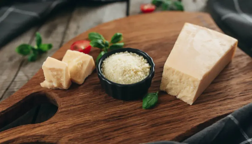 Kawałek parmezanu i starty ser w miseczce, idealne składniki, by dowiedzieć się, jaki ser do carbonary wybrać.