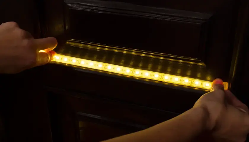 Montaż taśmy LED 12v na ciemnych meblach, tworząc subtelne oświetlenie w domu.