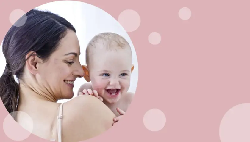 Uśmiechnięta mama tuli radosnego niemowlaka. Od kiedy oliwki dla niemowlaka? Pielęgnacja delikatnej skóry maluszka.