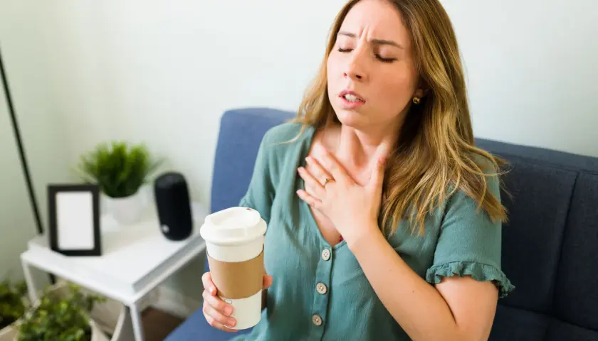 Donna con tachicardia, cerca di calmarla con un respiro profondo, tenendo una tazza.