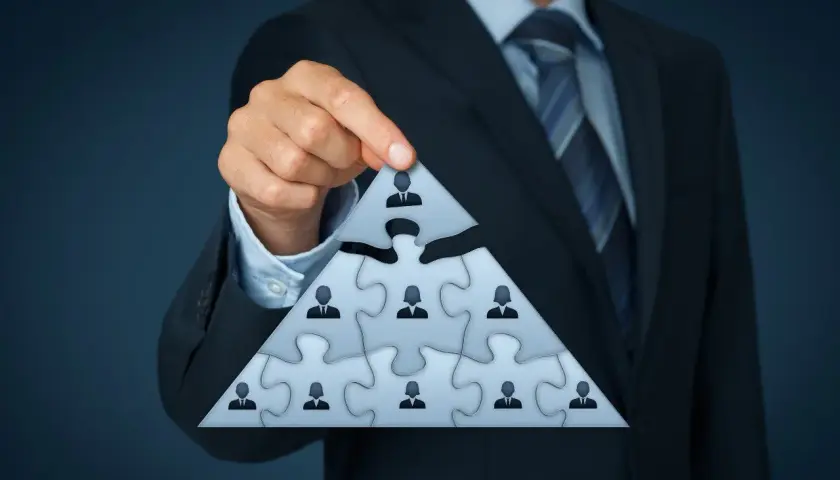 Biznesmen układa piramidę z puzzli, symbolizującą strukturę firmy i identyfikującą beneficjenta rzeczywistego.