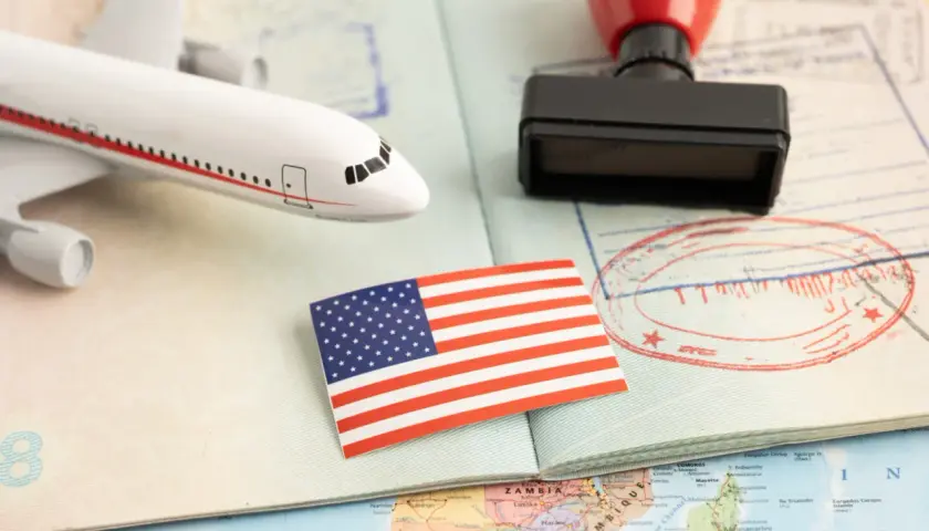 Flugzeugmodell, US-Flagge, Stempel und Pass auf einer Weltkarte. Perfekt für deine USA Reise Checkliste.