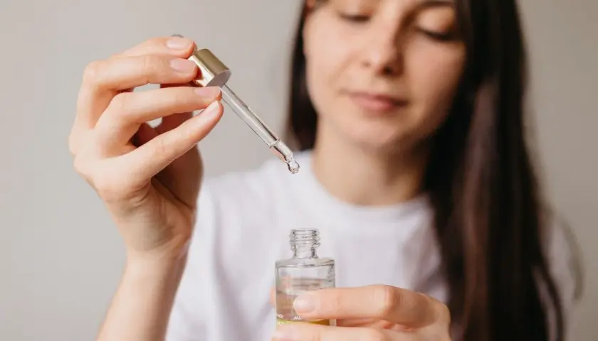 Kobieta aplikuje serum z niacynamidem, oczekując widocznych efektów poprawy kondycji skóry.