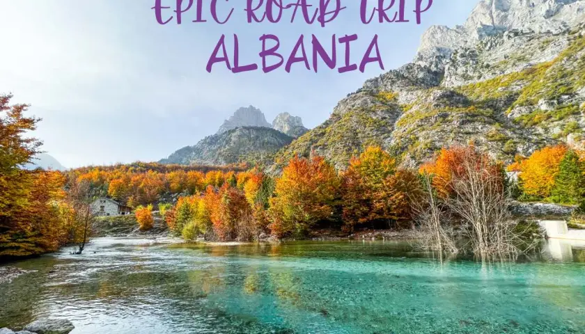 An epic road trip through Albania reveals a stunning turquoise river flowing past a stone house, with mountains and vibrant autumn foliage.