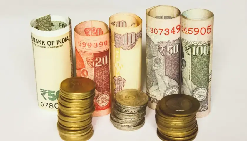 Zwijane banknoty i monety pokazują, jaka waluta w Indiach jest używana: rupie indyjskie o nominałach 5, 10, 20, 50 i 100.