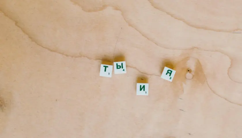 Litery "Ty" i "Я" na drewnianym tle. Zastanawiam się, jak ci minął dzień, co odpisać.