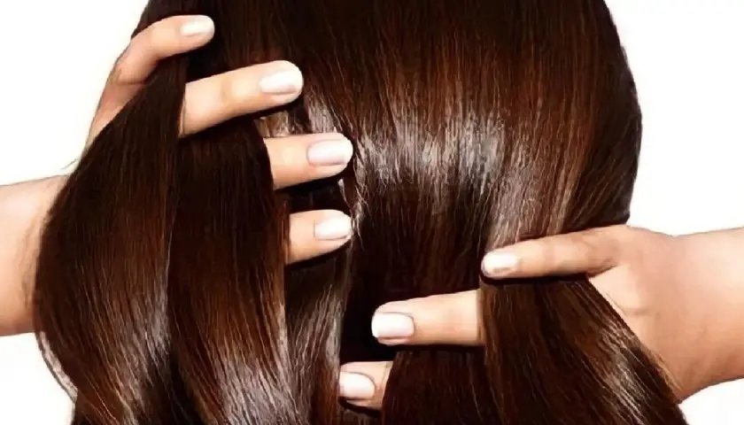 Manos peinando un cabello largo y sedoso de color chocolate.