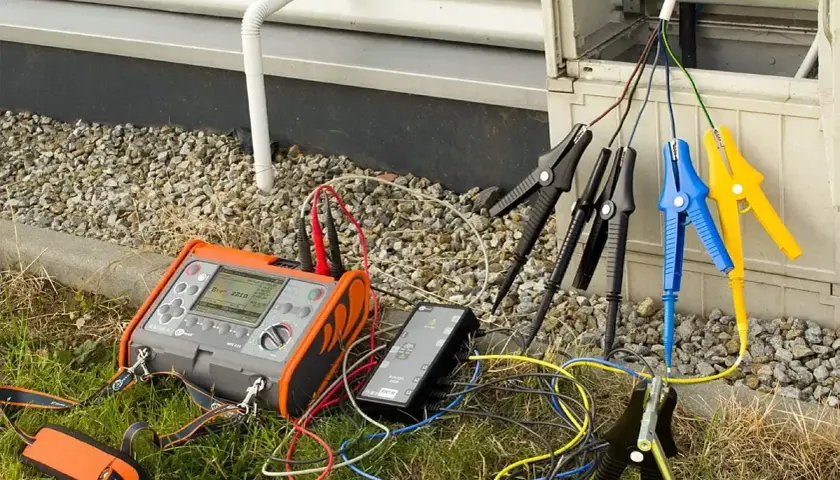 Przyrząd do pomiaru rezystancji izolacji podłączony do przewodów instalacji elektrycznej.
