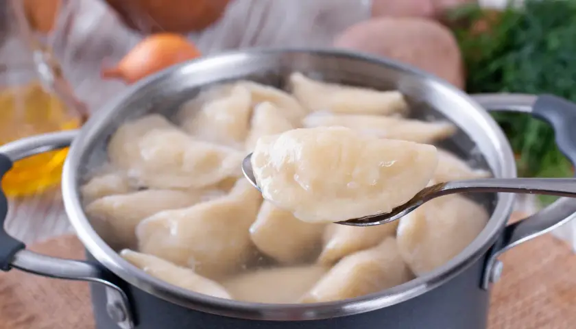 Gotowane pierogi w garnku, jeden na łyżce. Czy płukać pierogi po ugotowaniu? Zależy od przepisu!