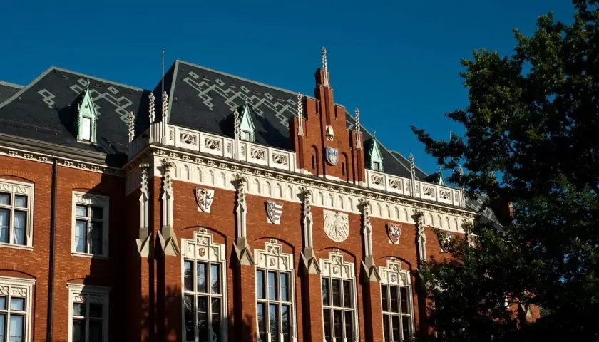 Elegancka fasada jednego z uniwersytetów w Krakowie, z charakterystycznymi detalami architektonicznymi i herbami.