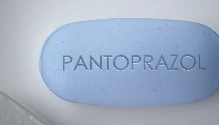 Ein hellblaues Pantoprazol-Tablett mit eingeprägtem Schriftzug. Manche Menschen nehmen Pantoprazol und Magnesium zusammen ein.