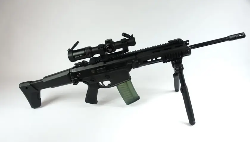 Czarny karabin z celownikiem optycznym Vortex Strike Eagle i zielonym magazynkiem. Kolimator do grota zapewnia precyzyjne celowanie.
