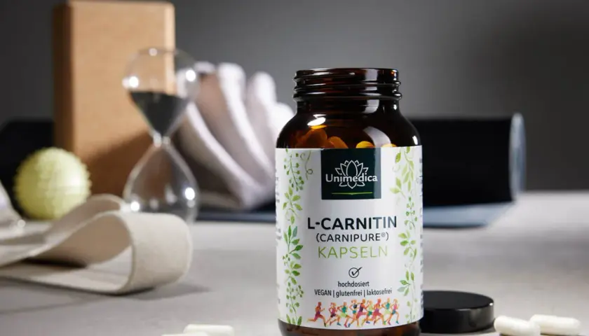 Flasche L-Carnitin Kapseln neben Yoga-Zubehör. Die richtige L-Carnitin Dosierung für dein Training.