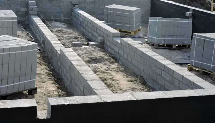 Budowa fundamentów z bloczków betonowych, widoczna izolacja pozioma fundamentów.