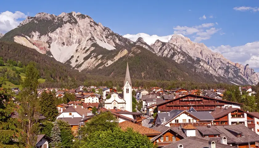 Charming Italy mountain towns nestled at the foot of majestic peaks. A church steeple rises above the rooftops.