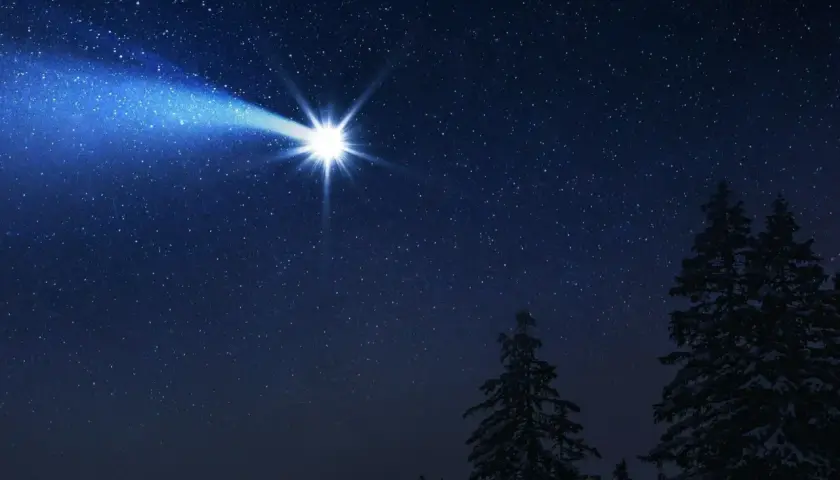 Jasna, oślepiająca gwiazda na pagonie nocnego nieba, świeci nad ośnieżonym lasem.