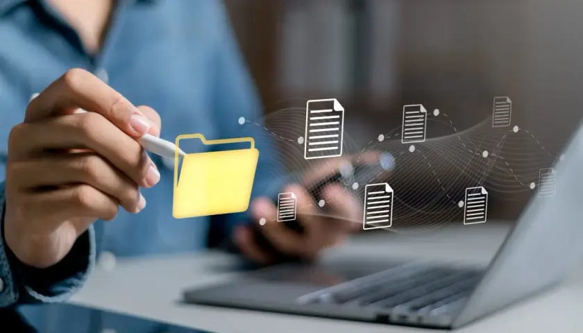 Main d'une personne utilisant un stylet pour interagir avec une icône de dossier jaune, symbolisant la digitalisation des processus et le flux de documents numériques.