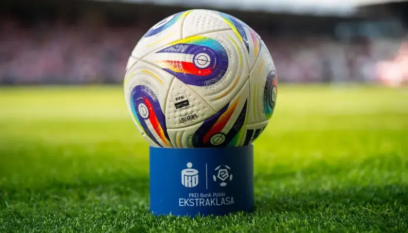 Piłka PKO Bank Polski Ekstraklasa na niebieskim postumencie. Czas odmierza, ile kolejek do końca sezonu.
