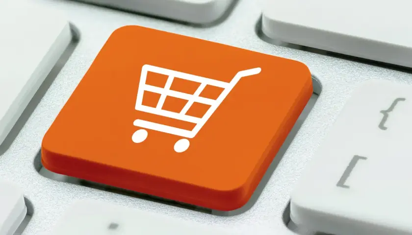 Pomarańczowy klawisz z ikoną koszyka na zakupy. To symbol e-commerce co to jest, czyli handlu elektronicznego.