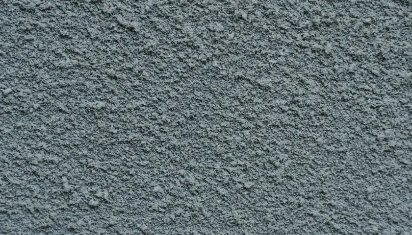 Dettaglio di pittura sabbiata grigia, con texture granulosa. Valutare i pro e contro di questo tipo di finitura per esterni.