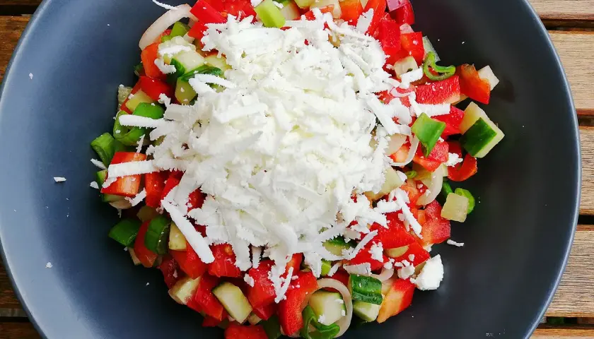 En fräsch sopska salata med hackad tomat, gurka, paprika och lök, toppad med smulad fetaost.