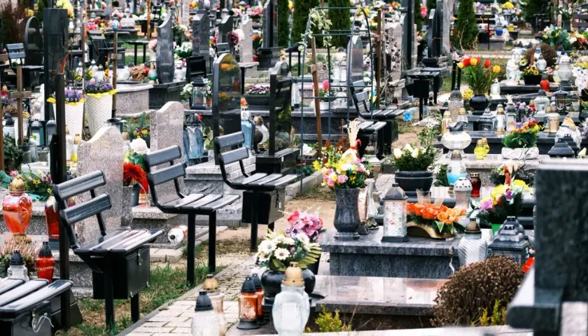 Ławki na cmentarzu, przygotowane na wizytę bliskich. Wiele zniczy i kwiatów świadczy o pamięci.