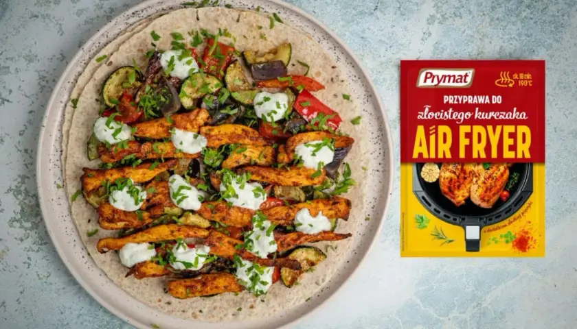 Gyros z kurczaka z warzywami i sosem na placku tortilli, obok paczka przyprawy Prymat Air Fryer.